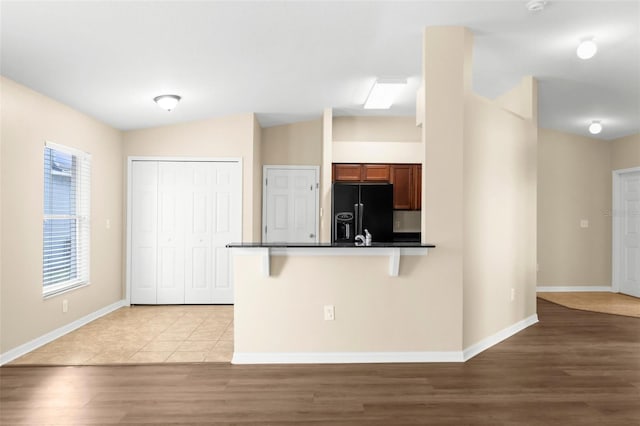 3410 Thistledown Ln, Land O Lakes, FL 34638 - kitchen featuring a breakfast bar area, baseboards, black fridge, a peninsula, and dark countertops