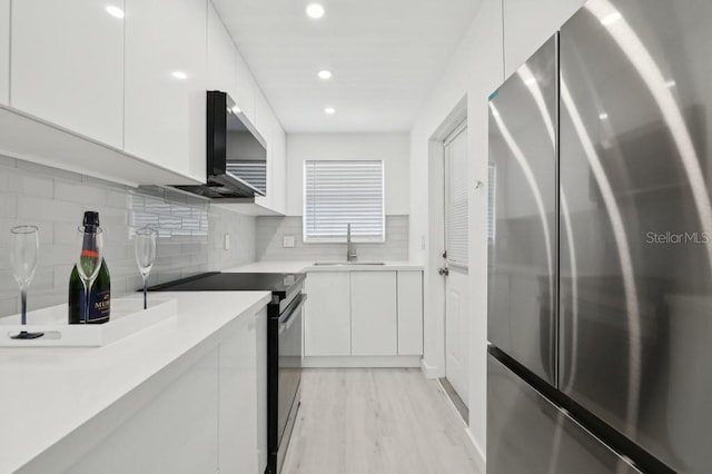 kitchen featuring modern cabinets, black electric range oven, a sink, freestanding refrigerator, and white cabinetry