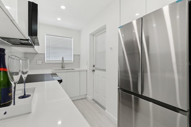 kitchen featuring white cabinets, a sink, freestanding refrigerator, light wood-type flooring, and modern cabinets