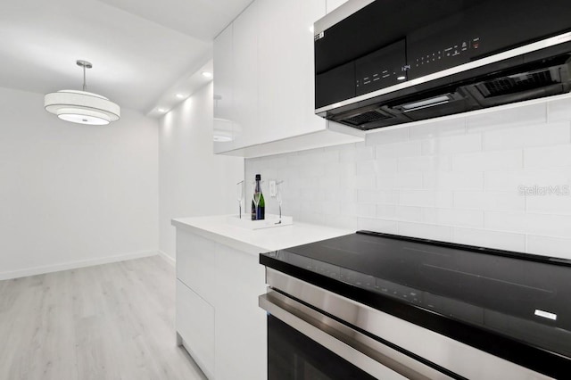 kitchen featuring light wood-type flooring, decorative backsplash, white cabinetry, and stainless steel microwave