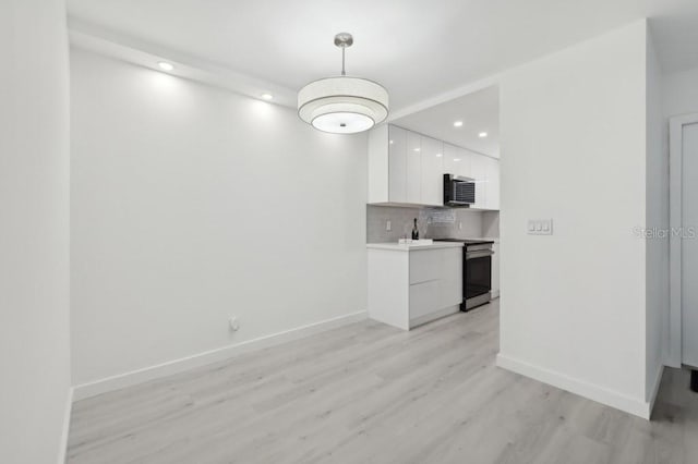 unfurnished dining area featuring baseboards, recessed lighting, and light wood finished floors