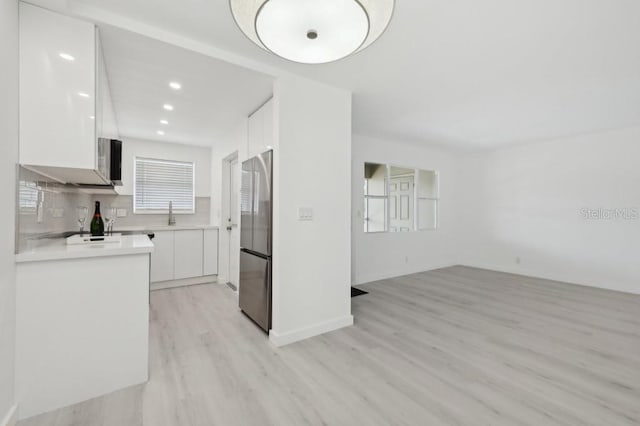 kitchen with light countertops, white cabinets, freestanding refrigerator, light wood finished floors, and recessed lighting