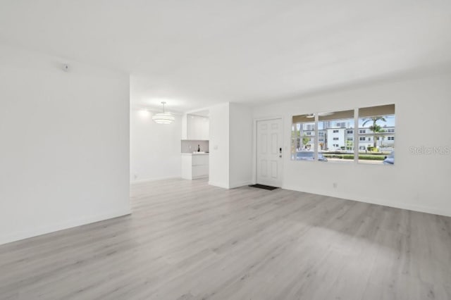 unfurnished living room with baseboards and light wood finished floors