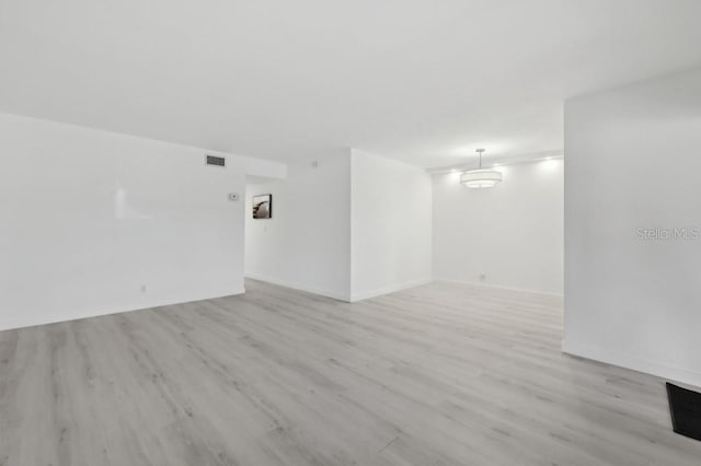 unfurnished room with baseboards, light wood finished floors, and visible vents
