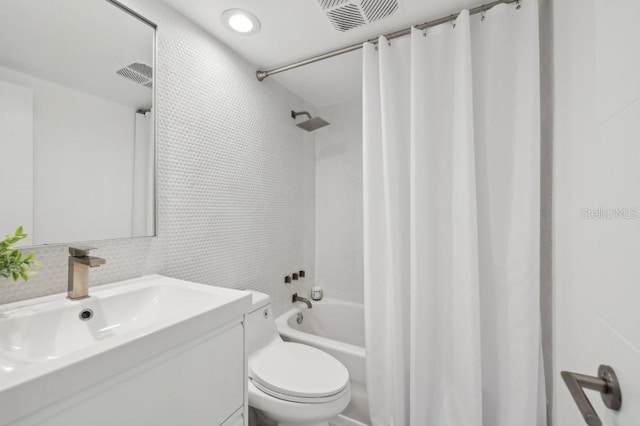 full bath with visible vents, shower / bath combo with shower curtain, vanity, toilet, and tile walls