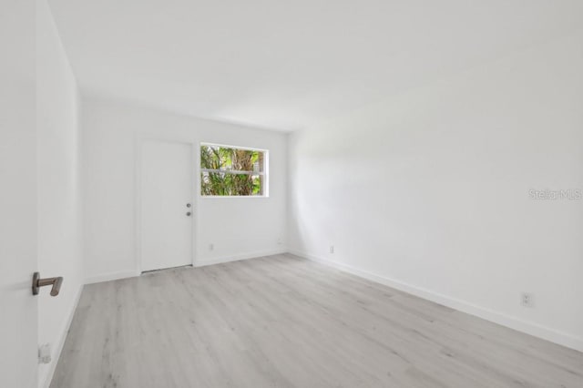 empty room with baseboards and light wood-type flooring