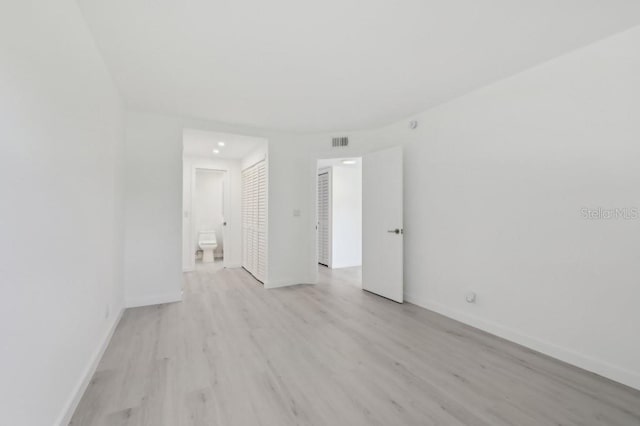 unfurnished room with baseboards, light wood finished floors, and visible vents