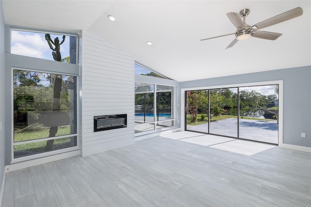 unfurnished living room featuring high vaulted ceiling, ceiling fan, wood finished floors, and a wealth of natural light