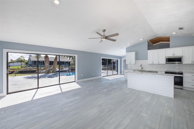 kitchen with visible vents, vaulted ceiling, a sink, stainless steel appliances, and white cabinetry