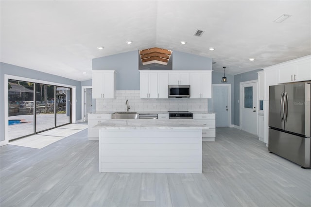 kitchen with visible vents, appliances with stainless steel finishes, tasteful backsplash, vaulted ceiling, and a sink