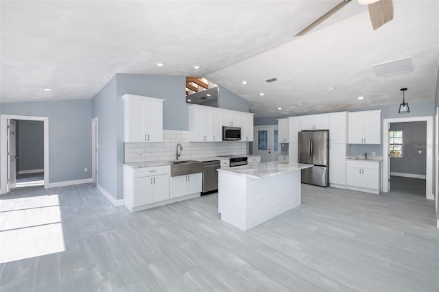 kitchen featuring baseboards, a sink, lofted ceiling, and stainless steel appliances