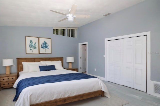 bedroom with a ceiling fan, wood finished floors, lofted ceiling, visible vents, and a closet