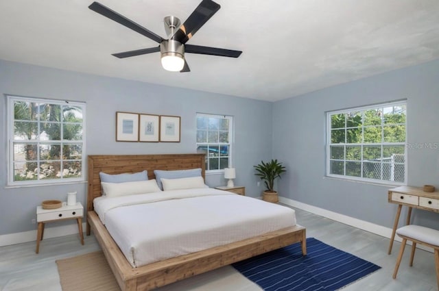 bedroom featuring baseboards, multiple windows, and ceiling fan
