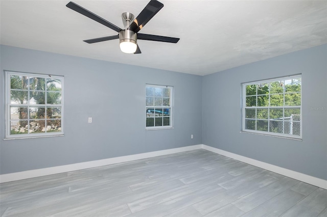 empty room with plenty of natural light, baseboards, ceiling fan, and wood finished floors