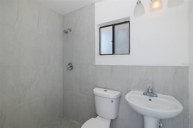 full bathroom with a sink, a tile shower, and toilet