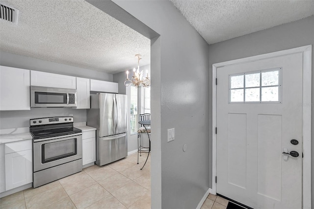kitchen with appliances with stainless steel finishes, a chandelier, a textured ceiling, and visible vents