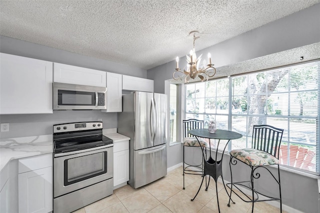 kitchen with a textured ceiling, white cabinets, an inviting chandelier, stainless steel appliances, and light tile patterned flooring