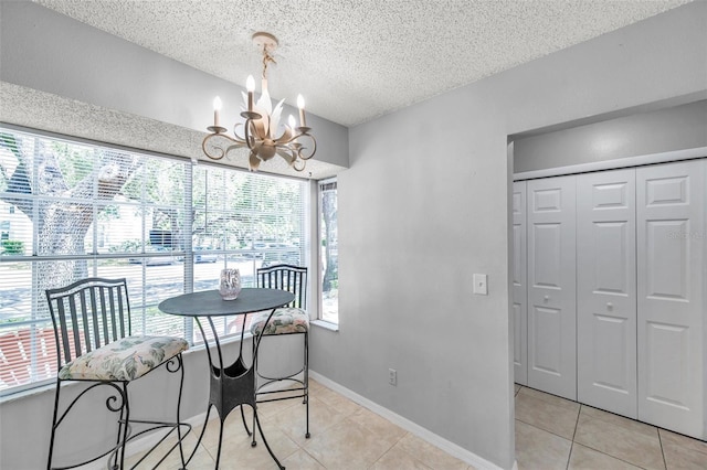 dining area with baseboards, a textured ceiling, light tile patterned flooring, and a notable chandelier