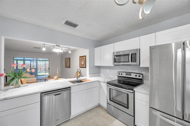 kitchen with a sink, appliances with stainless steel finishes, white cabinetry, and visible vents