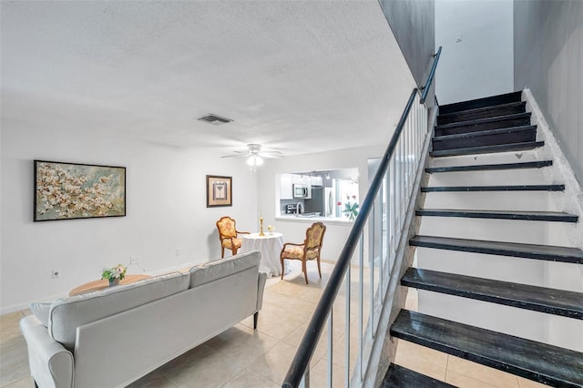 staircase with tile patterned floors, a ceiling fan, a textured ceiling, and visible vents