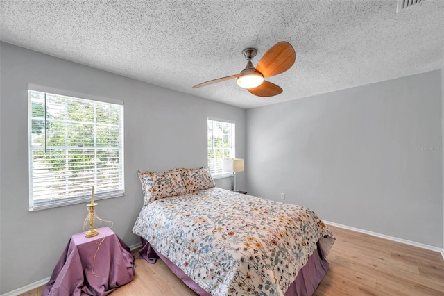 bedroom with visible vents, a ceiling fan, a textured ceiling, and light wood finished floors