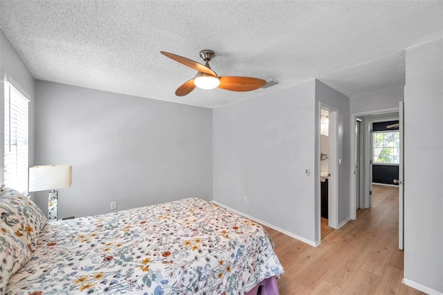 bedroom with visible vents, a textured ceiling, light wood finished floors, and baseboards