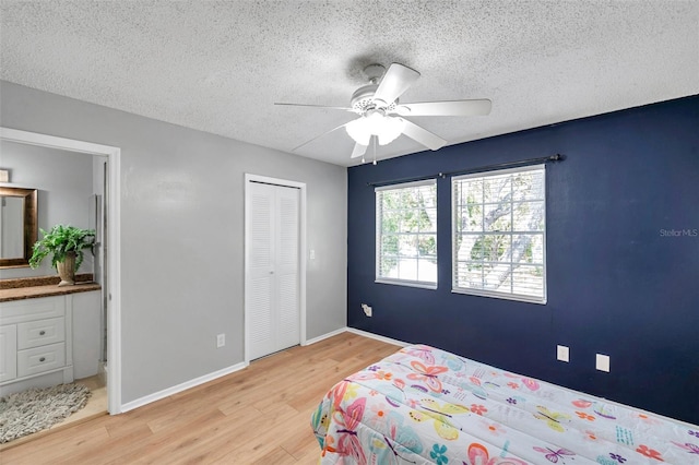 bedroom with ceiling fan, light wood finished floors, a textured ceiling, baseboards, and a closet