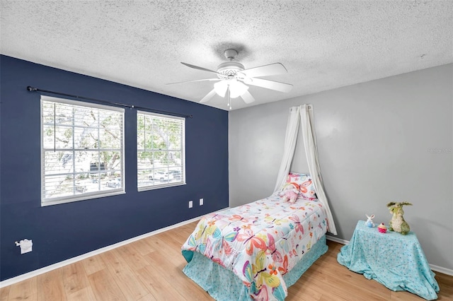 bedroom featuring a textured ceiling, baseboards, a ceiling fan, and wood finished floors