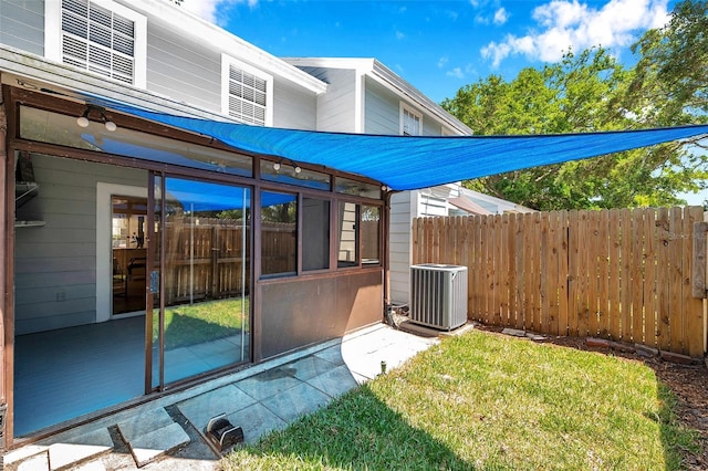 exterior space with a sunroom, central AC unit, fence, and a yard