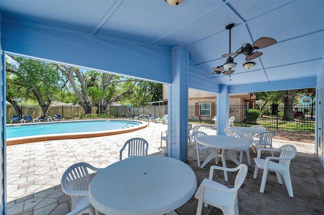 view of patio with a fenced backyard, a community pool, ceiling fan, and outdoor dining space
