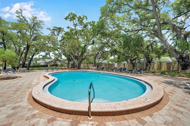 community pool with fence and a patio area