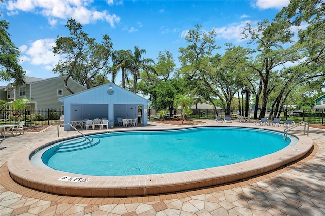 community pool with a patio area and fence