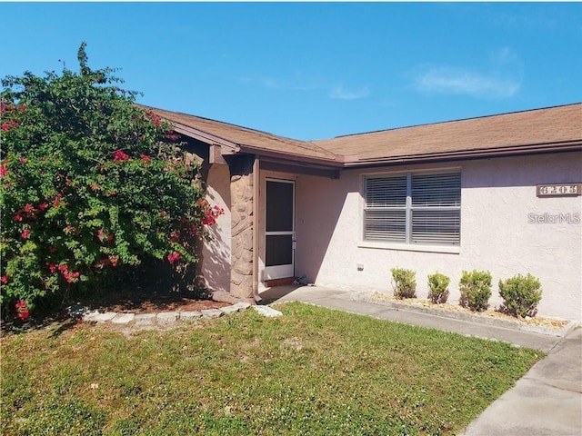 entrance to property with a lawn and stucco siding