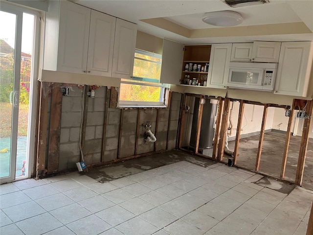 kitchen featuring white cabinets, open shelves, a raised ceiling, and white microwave