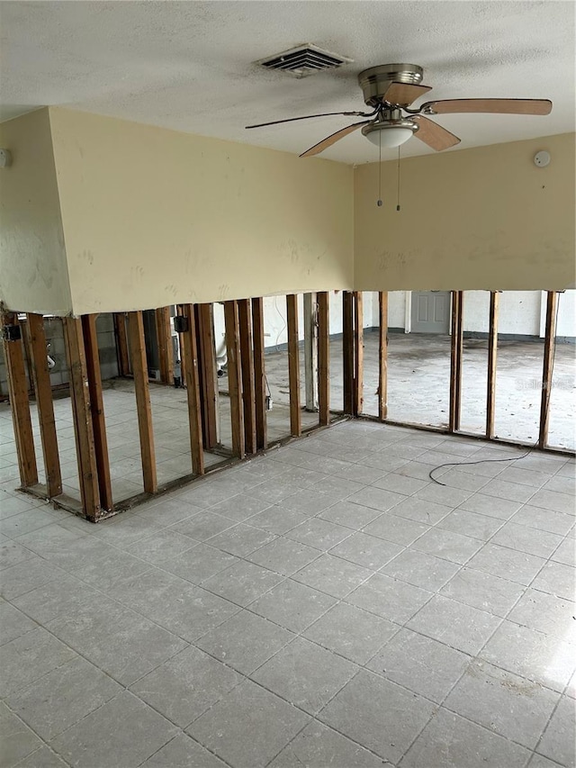 unfurnished room with visible vents, a ceiling fan, and a textured ceiling