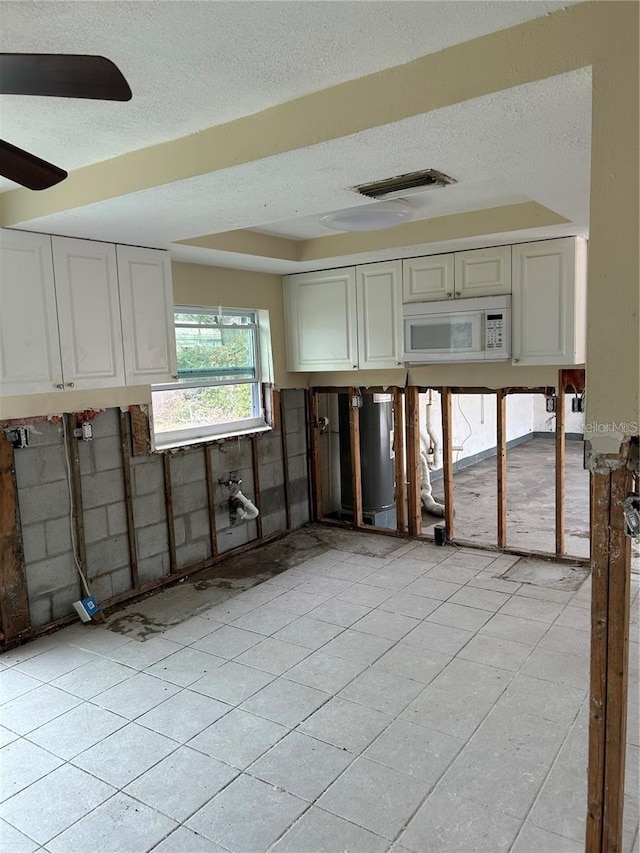 kitchen featuring visible vents, a textured ceiling, ceiling fan, and white microwave