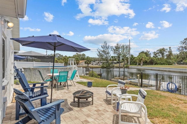 view of patio / terrace featuring a water view, an outdoor fire pit, a fenced backyard, and outdoor dining space