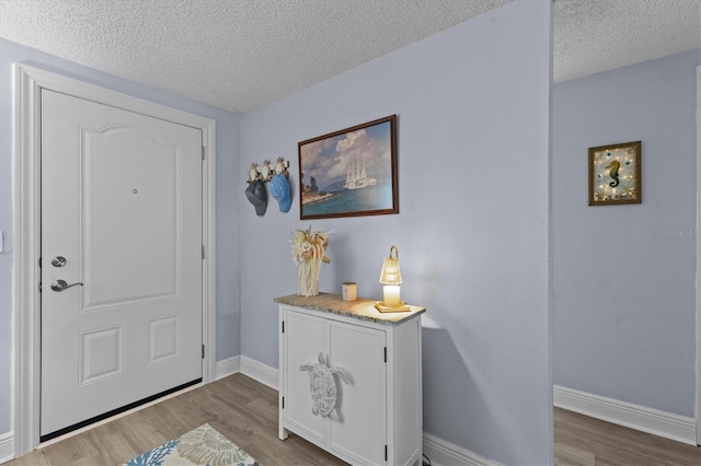 entryway with baseboards, a textured ceiling, and wood finished floors