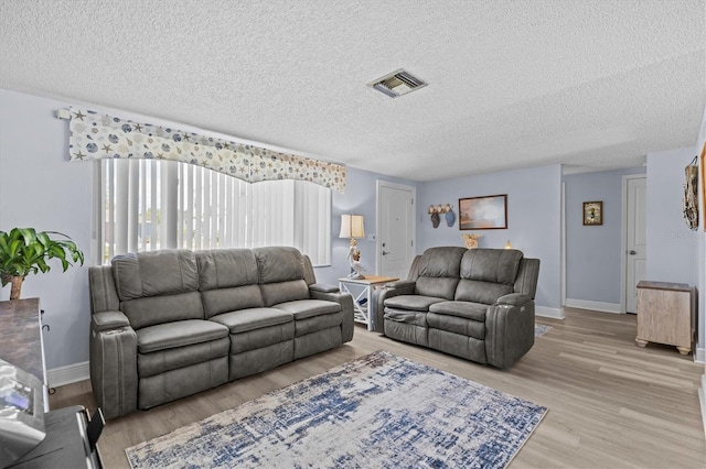living room with visible vents, a textured ceiling, and light wood-style floors