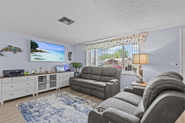 living area featuring a textured ceiling, visible vents, and wood finished floors