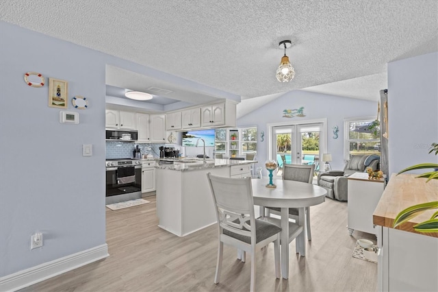 dining room featuring visible vents, lofted ceiling, light wood-style floors, baseboards, and a textured ceiling