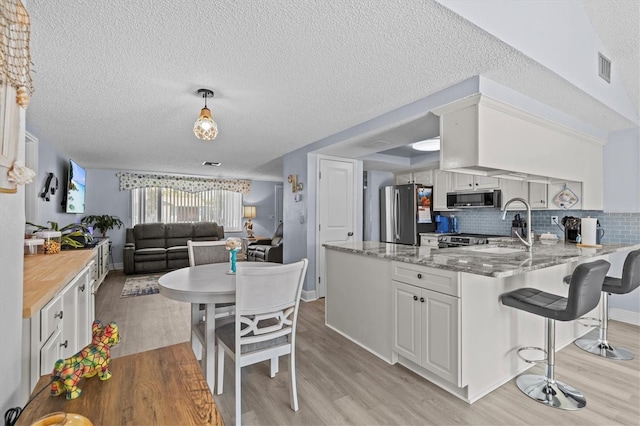kitchen featuring a peninsula, light wood-style flooring, appliances with stainless steel finishes, and a breakfast bar