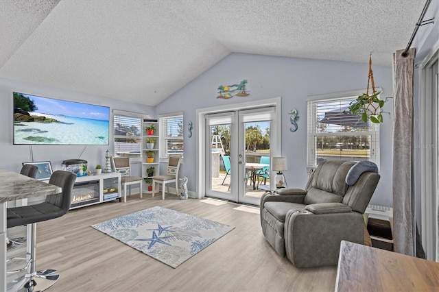 interior space featuring french doors, a textured ceiling, wood finished floors, and vaulted ceiling