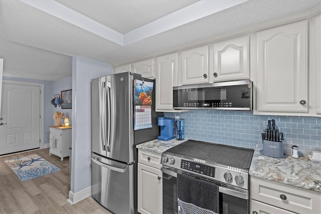 kitchen featuring tasteful backsplash, white cabinets, stainless steel appliances, and light wood-style flooring