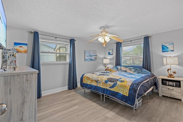 bedroom with baseboards, ceiling fan, light wood-type flooring, and a textured ceiling