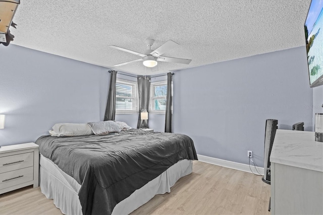 bedroom with light wood-style floors, a ceiling fan, baseboards, and a textured ceiling
