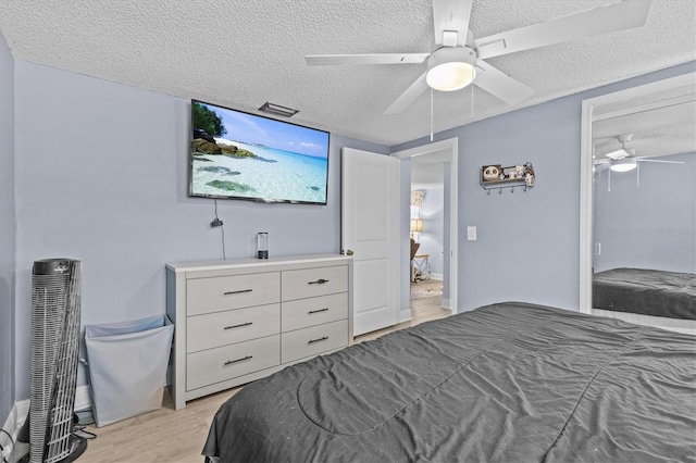 bedroom featuring ceiling fan, light wood-style flooring, and a textured ceiling