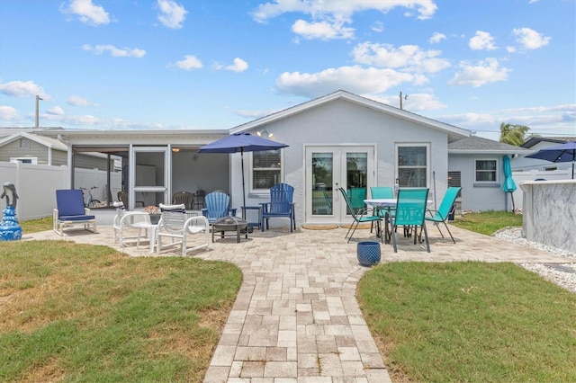 rear view of property featuring fence, a yard, a patio, a fire pit, and stucco siding
