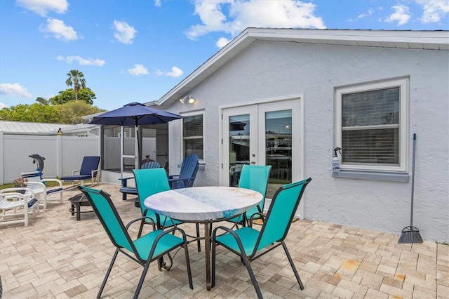 view of patio with outdoor dining area, fence, and french doors