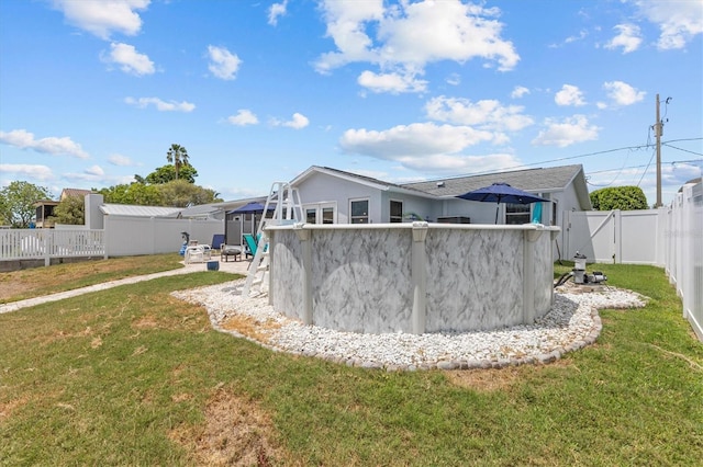 back of property featuring a fenced backyard, a yard, and a pool